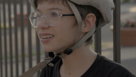 Cute-kid-in-a-bike-helmet-and-glasses-looks-up-and-off-camera-at-golden-hour