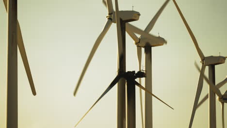 Ständige-Nahaufnahme-Von-Rotoren-Und-Flügeln-Von-3-Windkraftanlagen-Von-Hinten-In-Einem-Windpark-Während-Des-Sonnenuntergangs-In-Der-Nähe-Von-Palm-Springs-In-Der-Mojave-Wüste,-Kalifornien,-USA