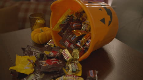 Close-Up-Tilt-of-a-Halloween-Candy-Spilling-from-a-Pumpkin-Pail