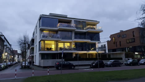 Luxuriöses,-Modernes-Wohngebäude-Mit-Lichtern-Im-Fenster-Bei-Bewölktem-Himmel-Im-Hintergrund