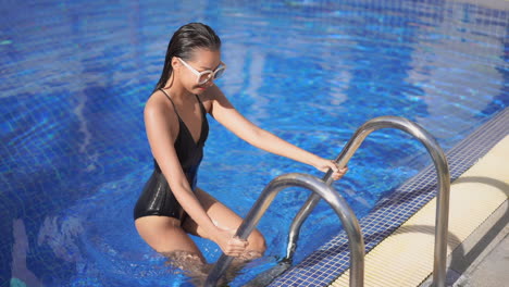 Attractive-Asian-woman-in-black-swimwear-comes-out-of-pool
