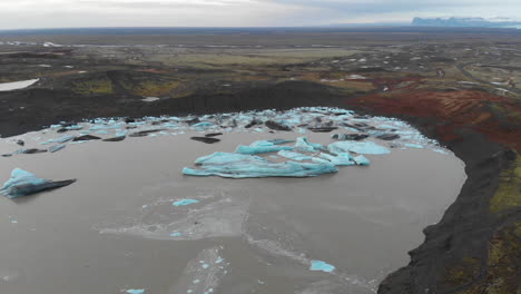 Luftaufnahme-Von-Eisbergen,-Die-Im-Gletscherseewasser-Im-Hochland-Von-Island-Schmelzen