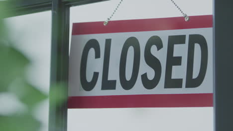 An-open-sign-in-the-window-of-a-business-is-flipped-to-the-side-labeled-closed