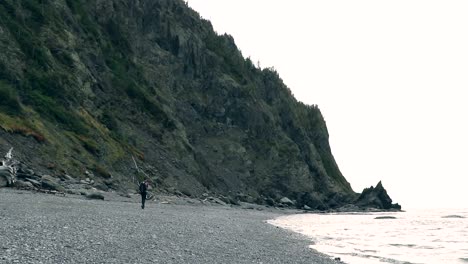 A-man-walks-alone-on-a-beach-near-a-cliff