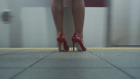 Una-Mujer-Con-Tacones-Rojos-Espera-Un-Tren-Subterráneo