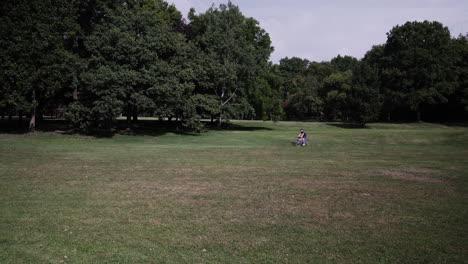 A-man-riding-his-bike-in-the-distance-through-a-grassy-field-with-trees
