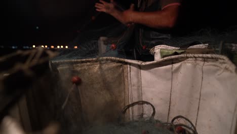 Tiefwinkelansicht-Aus-Einem-Korb,-Während-Ein-Fischer-Fischnetze-Herauszieht,-Um-Nachts-Einzustellen