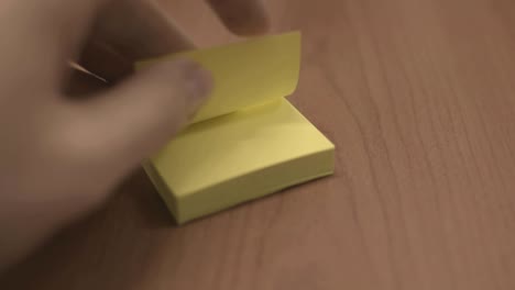 Rapidly-turning-yellow-sticky-note-pages,-taking-only-one