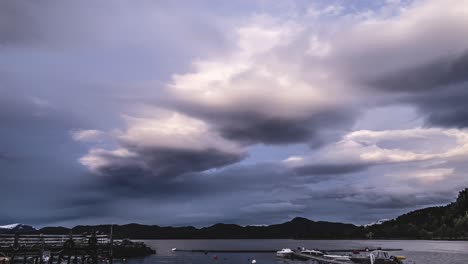 Thick,-gray-stormy-clouds-rushing-above-the-small-harbor-of-the-Magnillen-camping-at-dusk