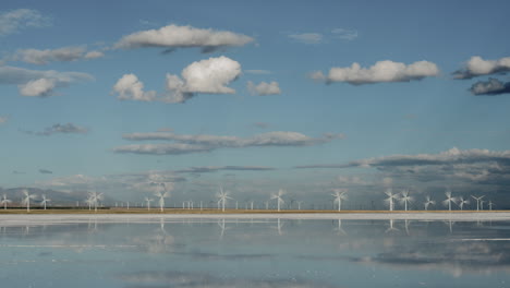 Wind-turbines-spin-near-the-water-under-a-blue-sky
