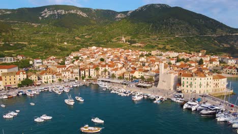 Panorama-of-a-coastal-town-with-many-houses-with-red-roofs,-surrounded-by-the-sea-and-mountains