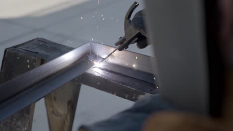Welding-metal-frame-while-sparks-are-shooting-away-close-up-in-slow-motion