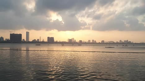 an-astonishing-view-of-the-sunset-and-the-drifting-clouds-above-the-water-with-the-city-on-the-background