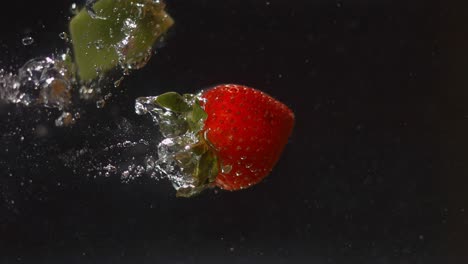 Eine-Erdbeere-Und-Ein-Stück-Kiwi-Werden-Ins-Wasser-Geworfen-Und-Sinken