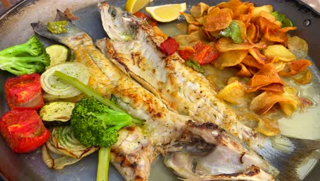 Grilled-sea-bass-with-crispy-potatoes-and-grilled-vegetables,-traditional-spanish-food-in-a-restaurant-in-Ibiza-Spain,-4K-shot
