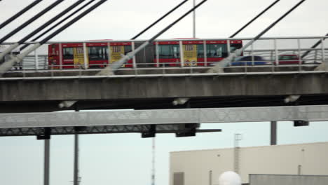 Red-articulated-bus-driving-on-a-suspended-bridge-over-Sydney-Harbour-in-Traffic-on-a