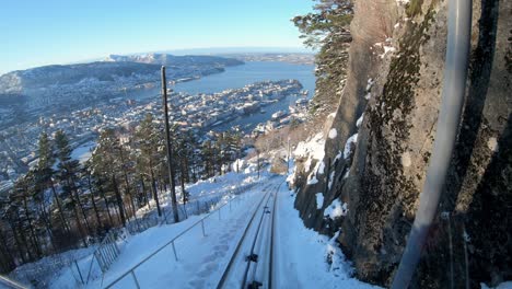 Inside-view-funicular-down-the-Mount-Floyen-covered-by-snow,-Bergen-City-as-background