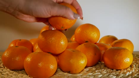 Die-Schöne-Weibliche-Hand-Greift-Eine-Orange-Aus-Dem-Orangenhaufen