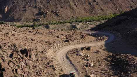 Vuelo-Sobre-El-Desierto-Y-Luego-Persiguiendo-Un-Automóvil-A-Lo-Largo-De-Un-Camino-A-Través-Del-Paisaje-Sombrío