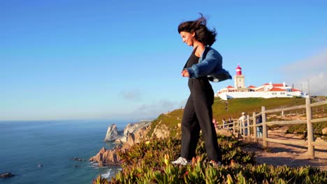 A-girl-stands-on-the-edge-of-a-cliff-enjoying-the-view-at-the-lighthouse-at-Cabo-da-Roca-in-Sintra,-Portugal