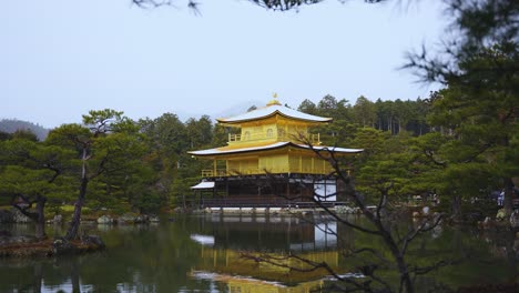 Goldener-Kinkakuji-Tempel-Mit-Schnee-Auf-Dem-Dach,-Der-Sich-Im-Teich-Widerspiegelt