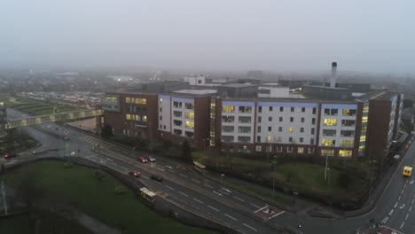 Aerial-view-British-NHS-hospital-on-misty-wet-damp-morning-mid-orbit-right