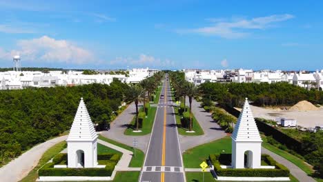 Flying-up-from-the-Alys-Beach-entrance,-a-lot-of-white-modern-houses-on-the-Gulf-of-Mexico-near-Seaside,-Panama-City,-and-Destin-Florida