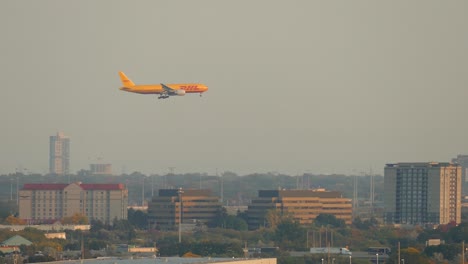 Tracking-shot-of-flying-DHL-airplane-over-Toronto-Cityscape-with-traffic-on-highway