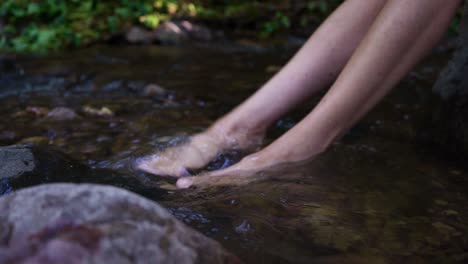 Feet-Immersed-In-The-Clear-Water-Of-A-Mountain-Stream---high-angle-shot