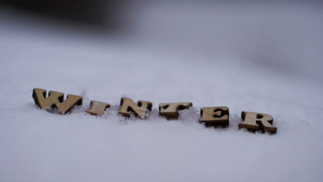 Nahaufnahme-Von-Buchstaben,-Die-Winter-Buchstabieren,-Wenn-Schnee-Herumfällt