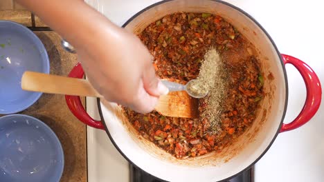 Adding-thyme-to-the-roux-gumbo-mixture-as-it-simmers-in-a-pot-on-the-stove---overhead-view-in-slow-motion-GUMBO-SERIES
