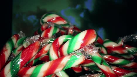 Moving-towards-a-large-pile-of-wrapped-red,-white,-green-mini-candy-canes