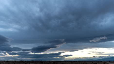 Layers-of-clouds-on-a-stormy-day-moving-in-different-directions-due-to-a-wind-shear-above-the-desert-landscape-at-sunset---time-lapse