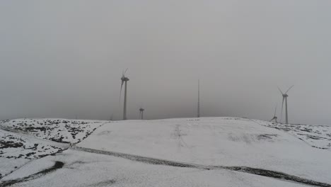 Campo-De-Montaña-De-Invierno-Turbinas-De-Viento-En-Tierras-Altas-Rurales-Vista-Aérea-Ventisca-Fría-Valle-Ladera-Creciente