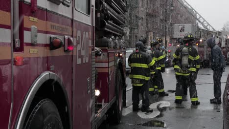 Firefighters-gathered-next-to-fire-engine-under-heavy-snowfall-in-Brooklyn-ConEd-Power-Cable-fire---Medium-slide-shot
