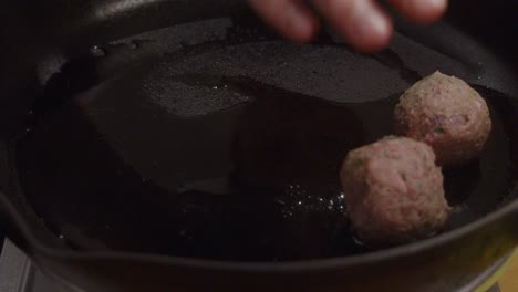 Adding-meat-balls-into-hot-frying-pan-with-cooking-oil