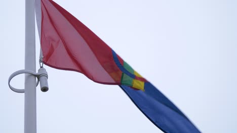 Sami-flag-colourful-flag-waving-on-top-of-pole-on-an-overcast-day---Low-angle-tilt-up-close-up