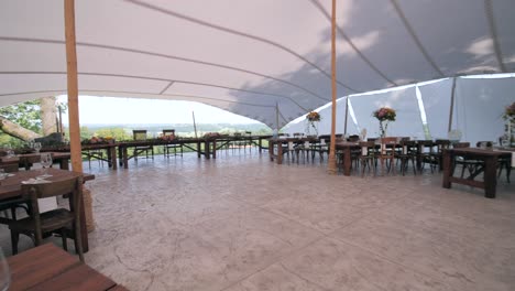 elegant-boho-chic-wedding-reception-setting-under-big-tent,-chairs-and-tables