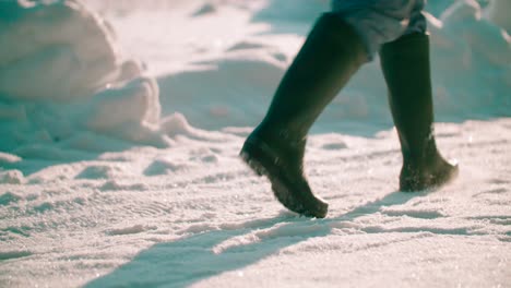 Close-up-view-of-a-person-walking-on-snow-on-a-sunny-day,-Lot-of-footprints-on-the-pathway