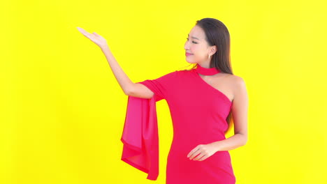 An-attractive-young-woman-in-a-red-off-the-shoulder-dress-gestures-with-her-hand-palm-up-to-one-side-of-the-frame