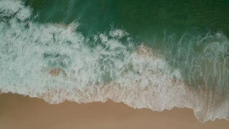 Aqua-waves-breaking-on-orange-beach-sand