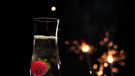 Erdbeerspritzer-Auf-Champagnerflöte-Mit-Wunderkerzen-Feuerwerk-Auf-Schwarzem-Hintergrund