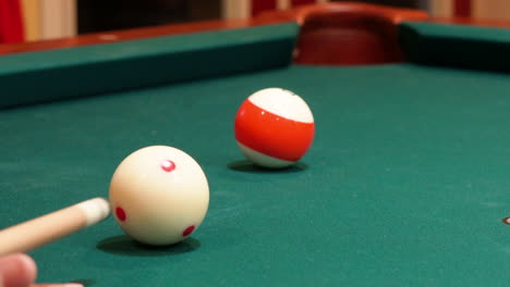 Closeup-of-Person-Playing-Pool-Shooting-Striped-Orange-13-Ball-into-Corner-Pocket-after-Practice-Strokes-using-Cue-Ball-with-Red-Spots,-Open-Bridge-Hand-with-Wooden-Cue-Stick-and-Green-Felt-or-Cloth