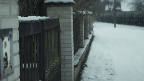Snow-falling-by-front-gate-in-residential-neighborhood,-Closeup-Detail-Shot