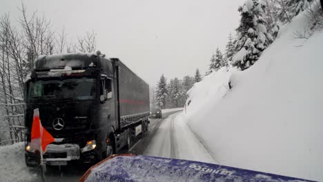 Truck-and-car-on-snowy-road-drive-through-a-snow-plow