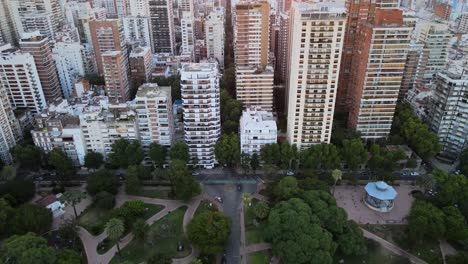 Dolly-in-flying-over-Barrancas-de-Belgrano-park-revealing-neighborhood-buildings-at-sunset,-Buenos-Aires,-Argentina