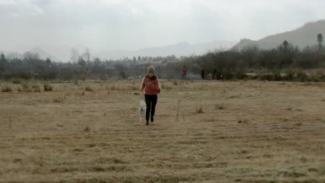 Mujer-China-Corriendo-Por-El-Campo-De-Tierras-De-Cultivo-Rural-Hacia-Drones,-Vista-Trasera