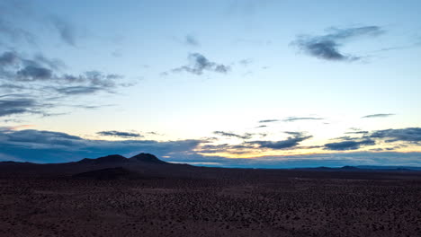 Pull-back-aerial-hyper-lapse-in-the-Mojave-Desert-with-mountains-in-the-otherwise-empty,-barren-landscape-at-sunset