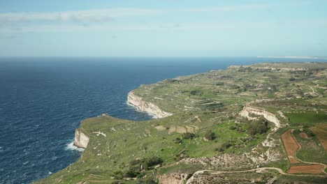 AERIAL:-Vast-Blue-Mediterranean-Sea-Wash-Dingli-Cliffs-with-Great-Green-Scenery-on-Hill