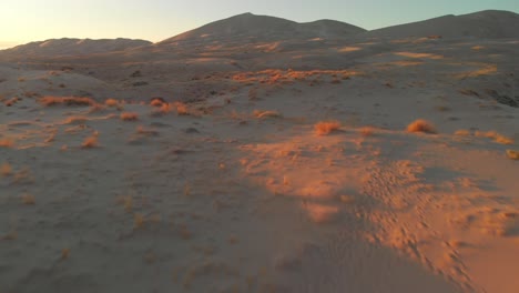 Desert-surface-during-sunset,-low-flight-over-Kelso-dunes-in-United-States